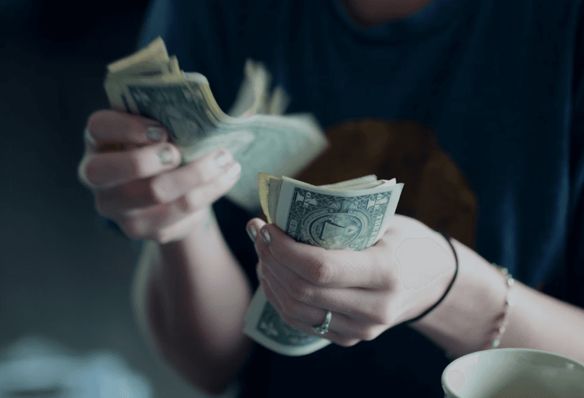 Person counting a stack of U.S. dollar bills 